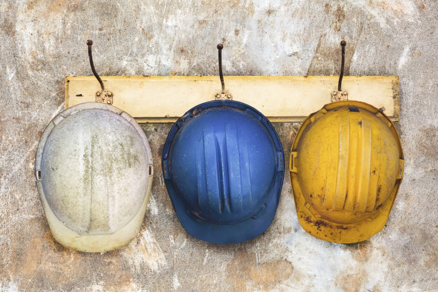 Three construction helmets hanging on an old wooden hat-rack